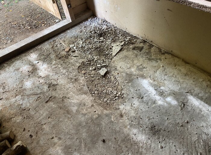 Trasigt betonggolv i uthus med skador på ytan och sprickor. Möjligt fuktproblem orsakat för länge sedan, som är stabilt men behöver åtgärdas.