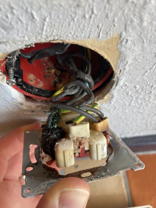 Smälta kablar och elektriska anslutningar innanför vägguttag uppvisar tecken på överhettning och potentiella elrisker.