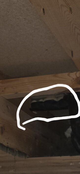 Isolerade vattenrör med mineralull och papp i träkonstruktion, omgivna av ståltråd. En vit linje markerar rörets placering.