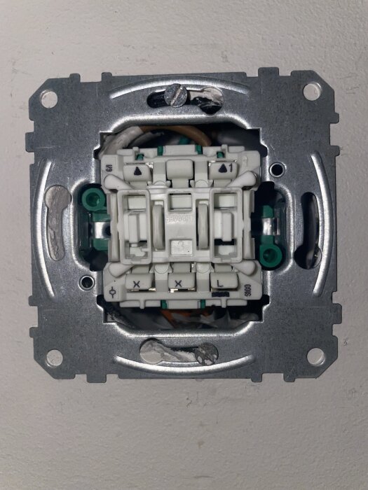 Elektrisk strömbrytare med flera anslutningskablar synlig bakom en öppen ram i vägg.