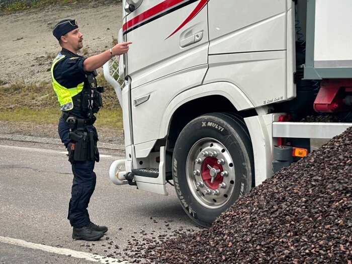 Lastbil har tappat last och blockerar körfält, polis diskuterar med föraren.