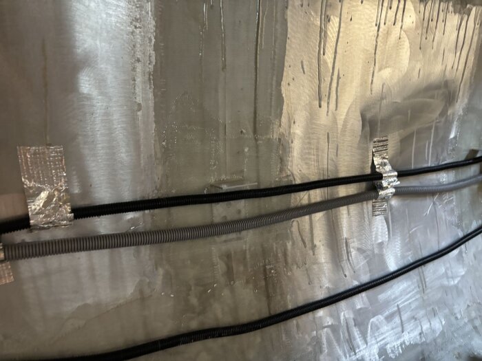 Aluminiumvägg med fästa slangar med hjälp av tejp, del av projekt för att installera bänkfästen i en vagn, med användning av skivor och bult.