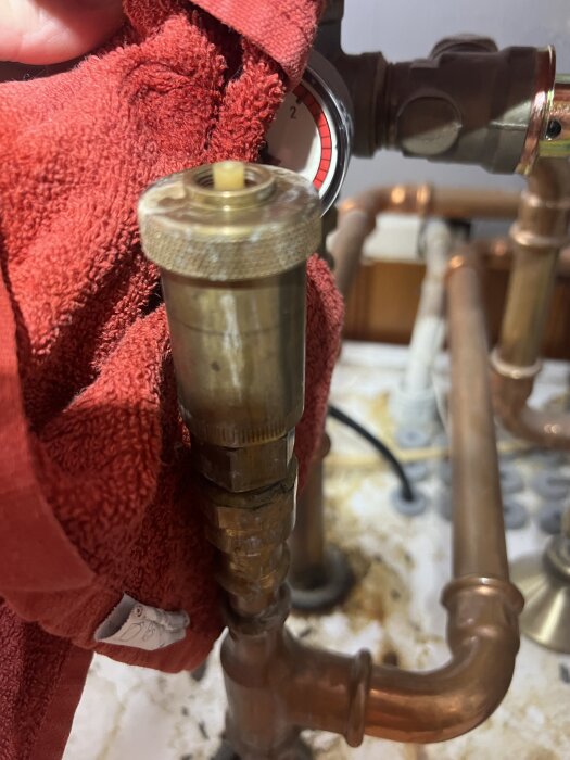 En säkerhetsventil med kopparrör, filtad med röd trasa, termometer i bakgrunden.