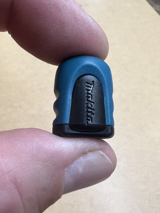 Blå och svart bits för skruvdragare med märket Makita ingraverat, hålls mellan två fingrar som visar storleken.