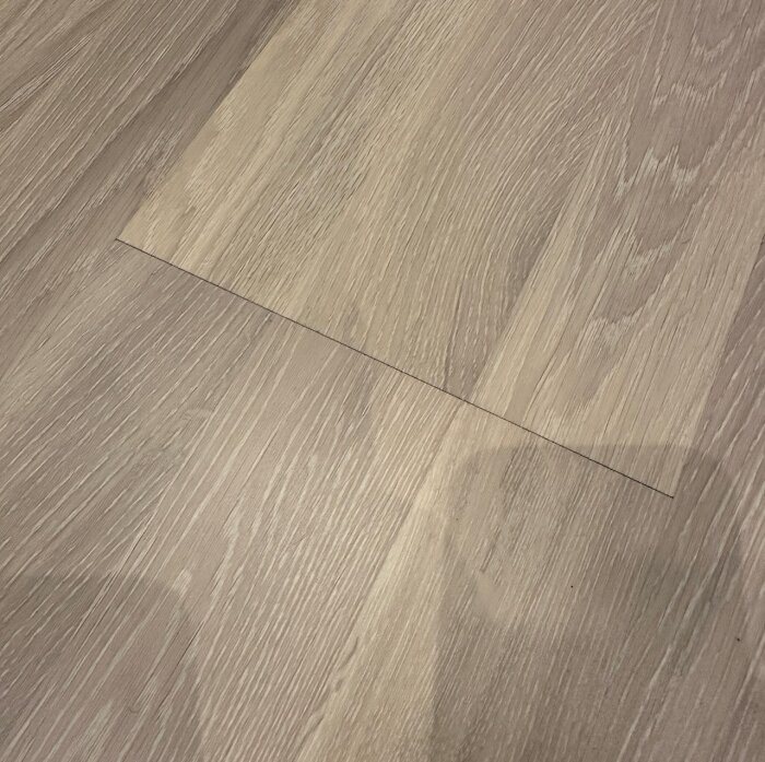 Närbild av parkettgolv med glipa mellan kortsidorna av två brädor.