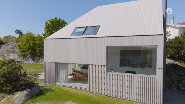 Modernt hus på Brännö med vinklad takdesign och stora fönster. Panelen på första våningen avviker utseendemässigt från resten.
