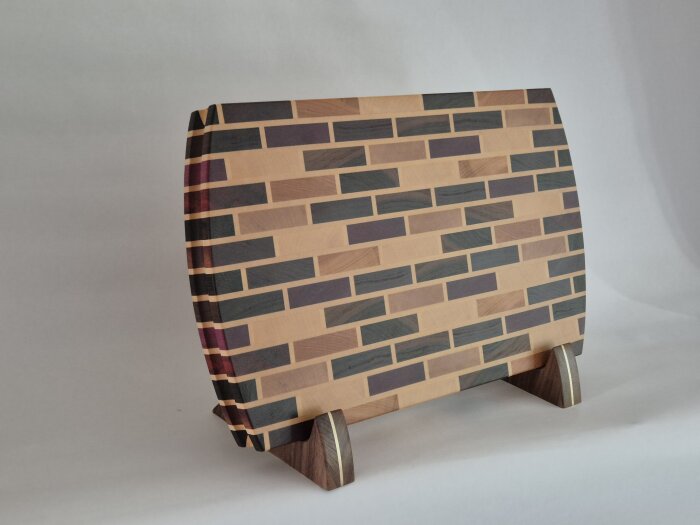 Skärbräda av exotiska träslag i ett mönster på ett ställ av valnöt med infälld mässing.