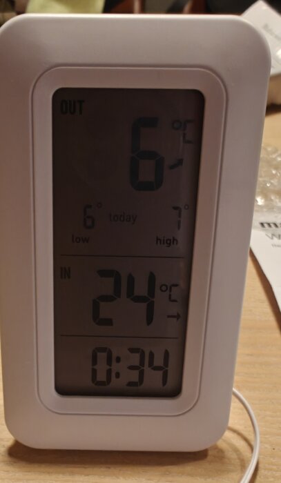 Digital termometer med utetemperatur 6°C och innetemperatur 24°C. Tiden visas som 0:34 i displayen.