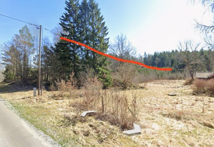 Landskap med skog och ledningstråd som sträcker sig över trädtoppar, gräsmark i förgrunden och ett hus tak synligt i kanten.