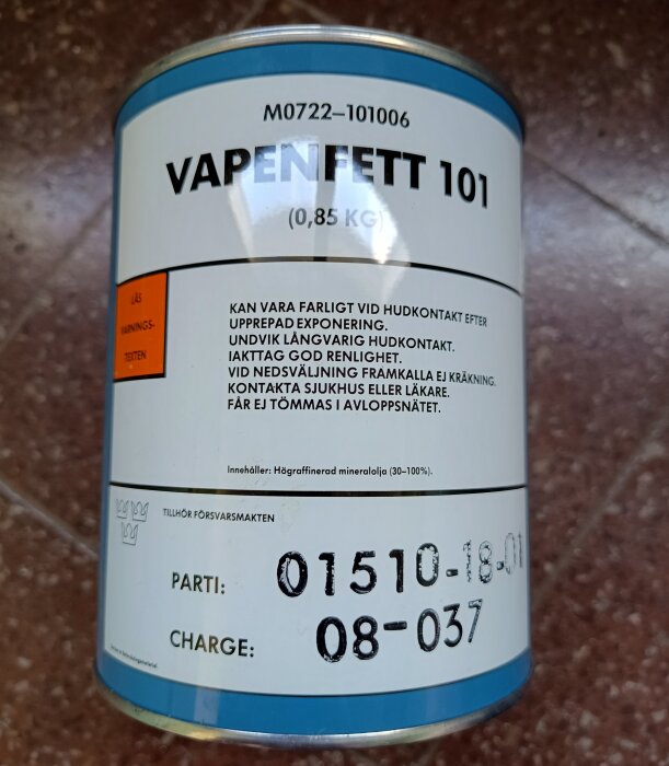 Burk med vapenfett, etikett visar Vapenfett 101, 0,85 kg. Varningsinformation om hudkontakt och instruktioner om säker användning.