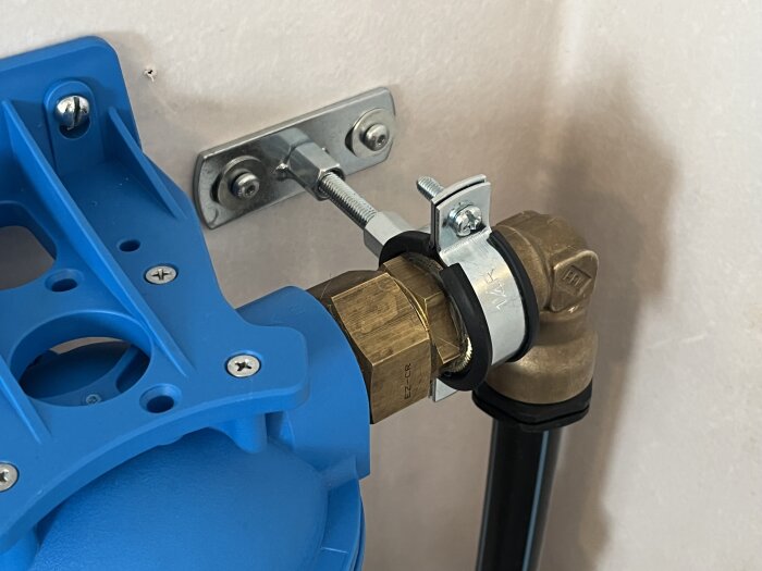 Blått plastfäste och metallklämma kopplade till en mässingsventil.