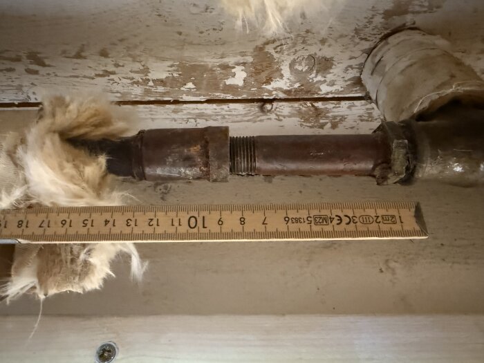 Rustigt rör med linjal för mätning, omgivet av isoleringsmaterial.