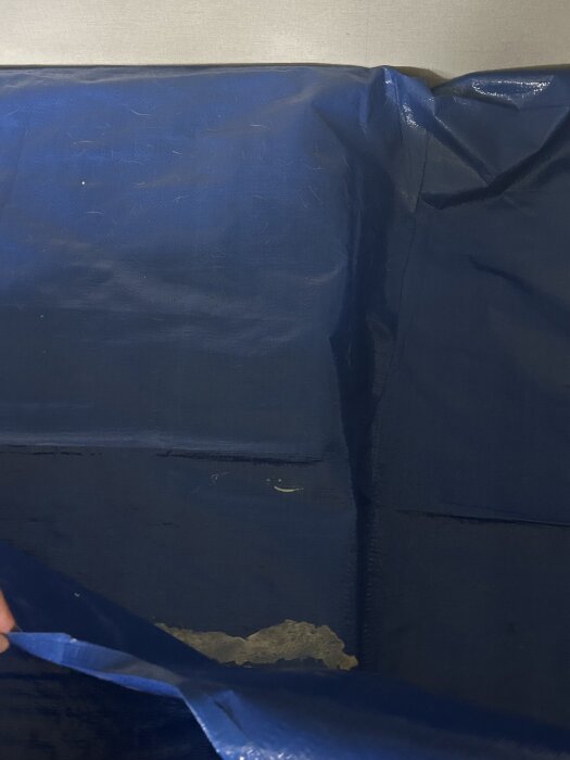 Blå presenning med försök att limma ihop för vattentäthet och UV-beständighet, två produkter testade utan framgång.