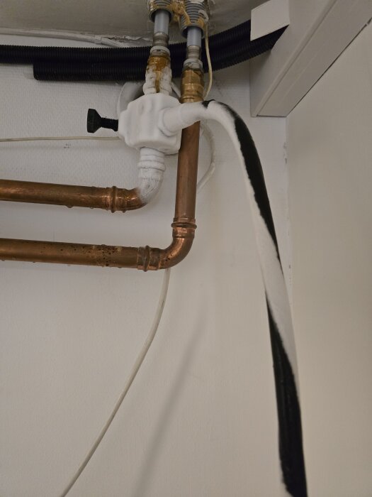 Kopparrör i ett rum med frostskydd och tecken på vattenläckage, synligt frysblock på ventilen.