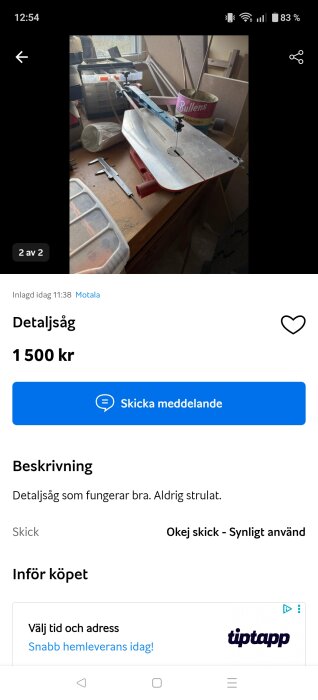 Bänkmonterad detaljsåg med metallbord och justerbar arm, omgiven av verktyg och en plåtburk på ett träbord nära ett fönster.