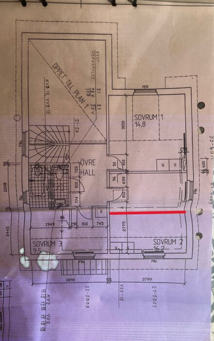 Planlösning med en föreslagen avdelande vägg markerad i rött mellan två sovrum i ett hus.