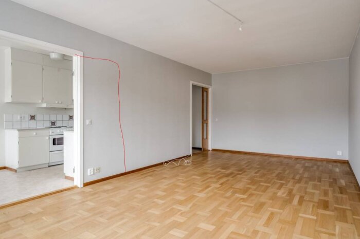 Vardagsrum med parkettgolv och anslutande kök. En röd linje markerar var en dörröppning planeras att breddas.