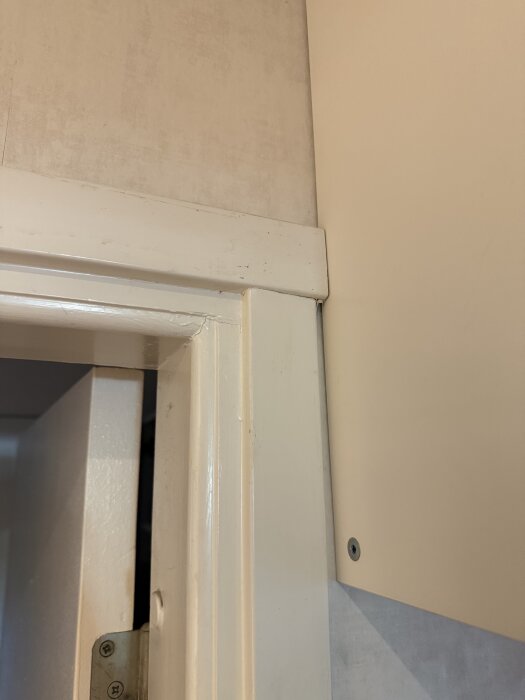 Vit dörrkarm och väggkonstruktion syns där dörren möter ett skåp. Diskuteras hur man drar en nätverkskabel mellan metallkarmen och väggen.