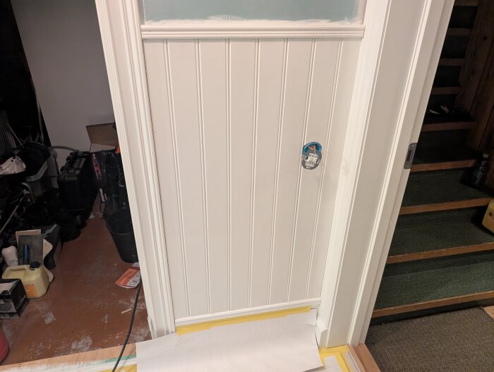 Målad pärlspontpanel med pågående grund- och täckfärgsmålning. Maskeringstejp och golvskydd syns vid basen av väggen.