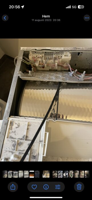 Närbild av en tvättmaskins inre med en delvis avhängd rem och elektroniska komponenter synliga.