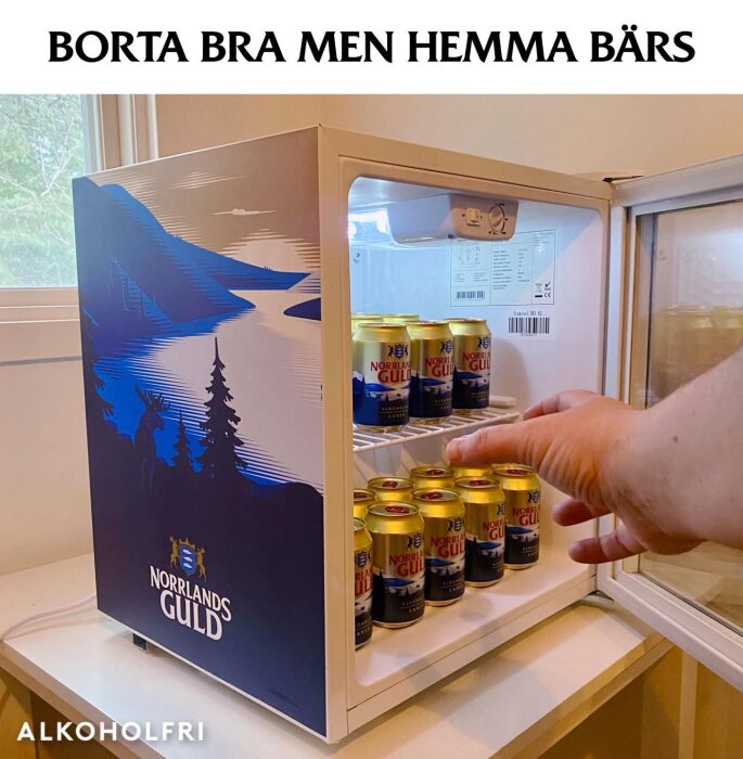 Minikyl med Norrländska Guld ölburkar, en hand tar en burk, texten "Borta bra men hemma bärs" ovanför.