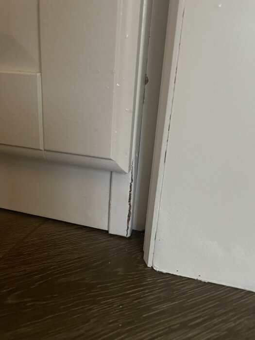 Vattenläckage synligt vid golvlist och vägg i ett renoverat hus från 1800-talet, med fuktgenomslag på väggens yta.