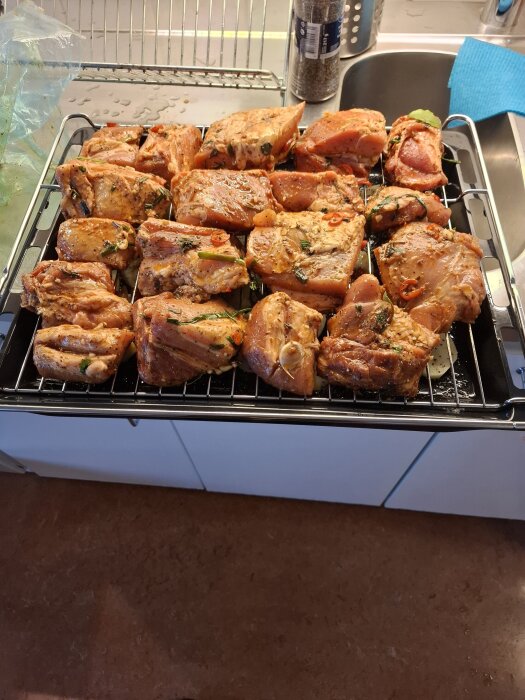 Ekologiska revbensspjäll marinerade med olivolja och kryddor, redo för tillagning på galler i köket.