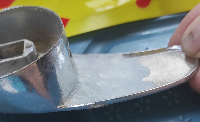 Brutet tvättställsblandarevred med skadad krom, tillfälligt lagat med superlim och bikarbonat, mot en gul bakgrund.