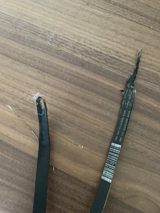 Trasig rem ligger på ett brunt trägolv.