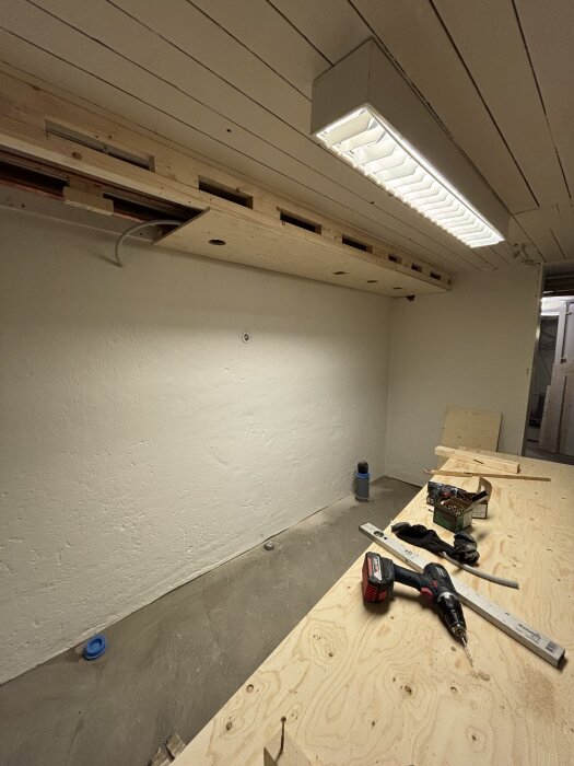 Flexslang och verktyg vid borrning för spotlights i ett trävalv inomhus.