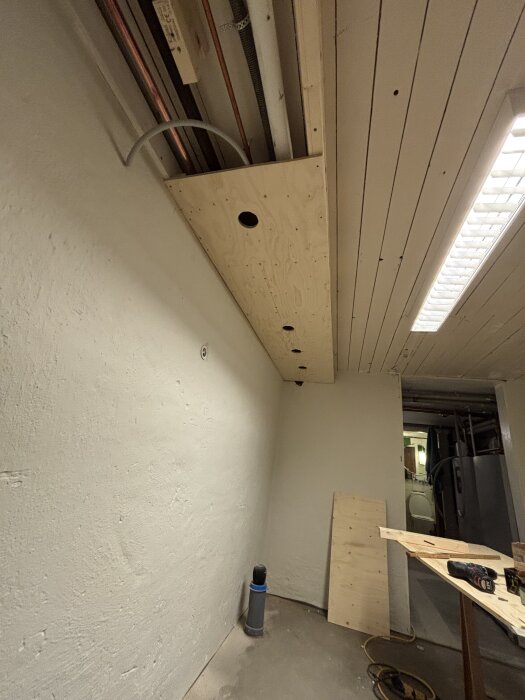 Tak med borrade hål för spottar och flexslang, en pågående installation för belysning. Verktyg och material syns i bildens förgrund.
