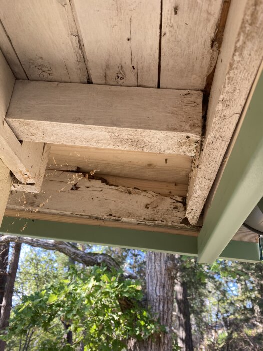 Närbild av ett hus med delvis skadat undertak i trä, omgiven av träd. Frågeställaren känner sig osäker på resultatet av plåttaket.