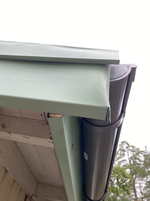 Falsat plåttak och takränna i närbild, installerat på en byggnad.