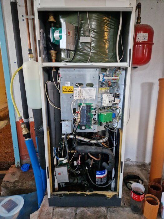 Öppen centralvärmepanna med synliga rör och elkopplingar, diskussion om att fästa spännband.