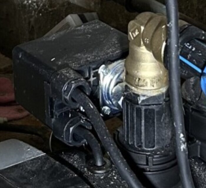 Svart tryckströmbrytare monterad ovanpå en pump, ansluten med kabel.