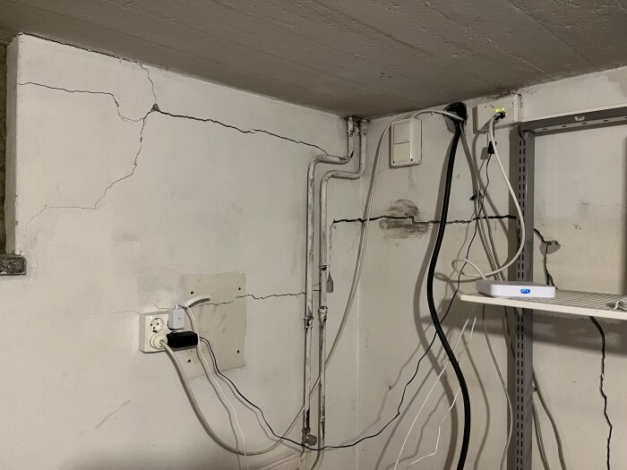Vägg med sprickor och flera kablar som hänger.