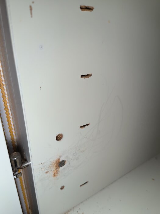 Skåpvägg med flera skruvhål och en fastspikad spik vars huvud är svårt att ta bort, enligt inlägget.