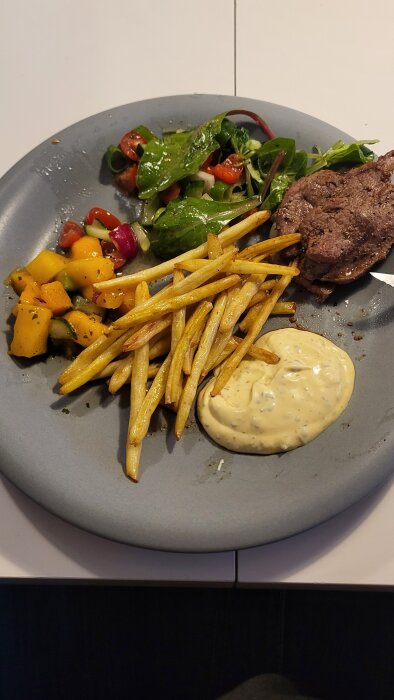 Tallrik med kalvstek av älg, sallad, smörslungade primörer, mangosalsa och bearnaisesås.