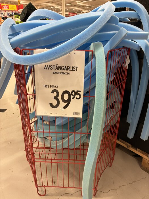 Blå avstängarlister i en röd metallkorg med priset 39,95 kronor, i en butiksmiljö.