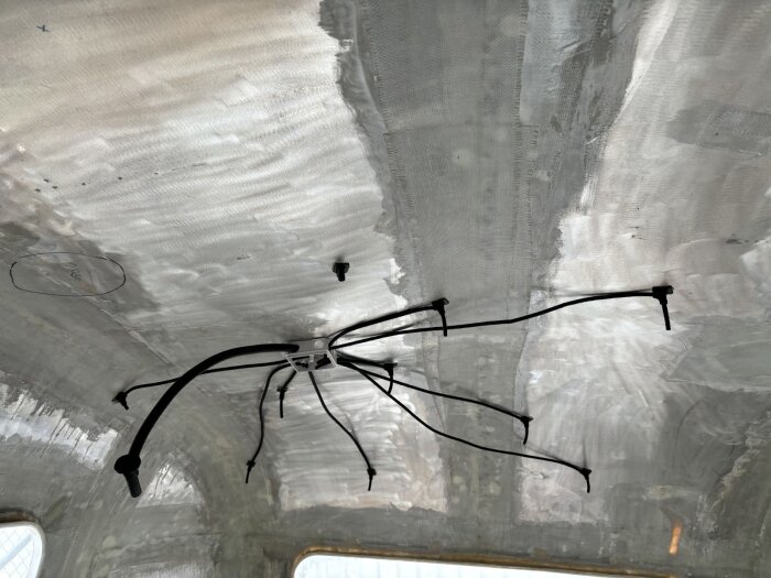 Elinstallation i taket med kabeldragning som sträcker sig från en central punkt i form av flera kablar fästa vid ett grått metalltak.