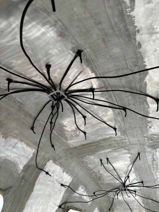 Elkablar uppsatta i taket av en vagn, formade som två spindelliknande strukturer förbereder stjärnhimmelseffekt.