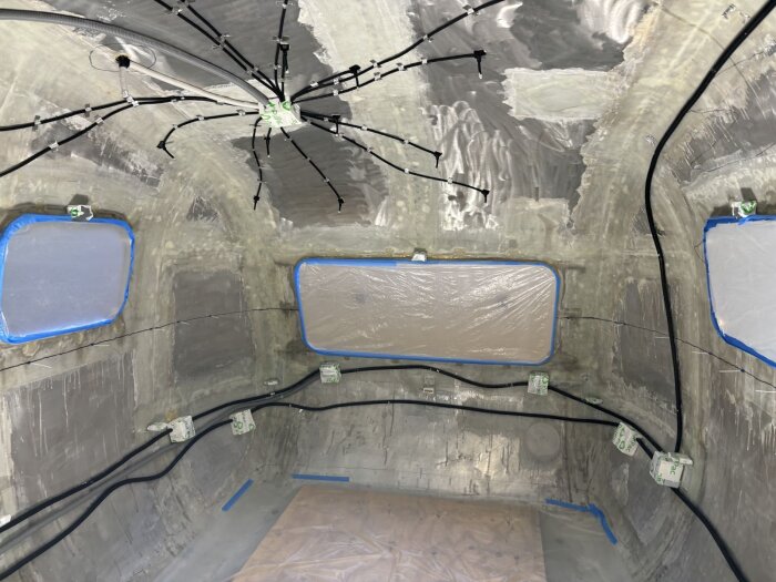 Vagntak med elslangar och dosor förbereds, slikkande tentakelliknande mönster. Väggar och tak är förberedda för isolering och kablage.