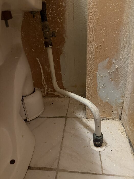 Bild av golvanslutning och rör vid toalett, visar behov av att förhindra vattenläckage vid borttagning för tapetsering.