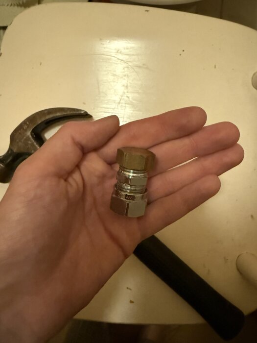 En hand håller en röranslutning eller plug av metall som ansluts för att förhindra vattenläckage när en toalett tas bort.