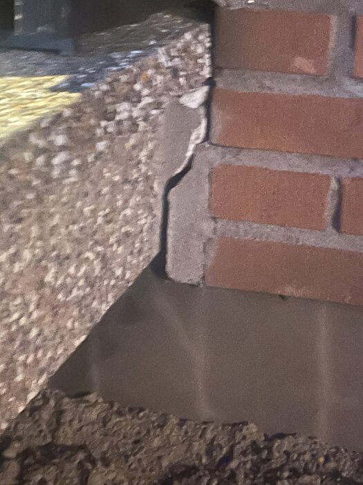 Trappa med spricka mellan betong och tegel.