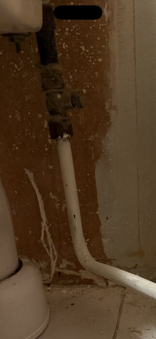 Sliten vattenventil och rör mot en vägg i ett rum.