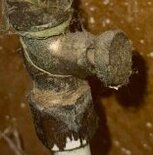 Gammal nålventil med rost och smuts i närbild på ett kopparrör.