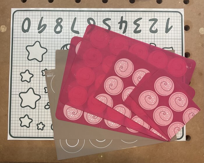 Bakplåtsdukar i silikon med olika mönster ligger utspridda på ett bord.