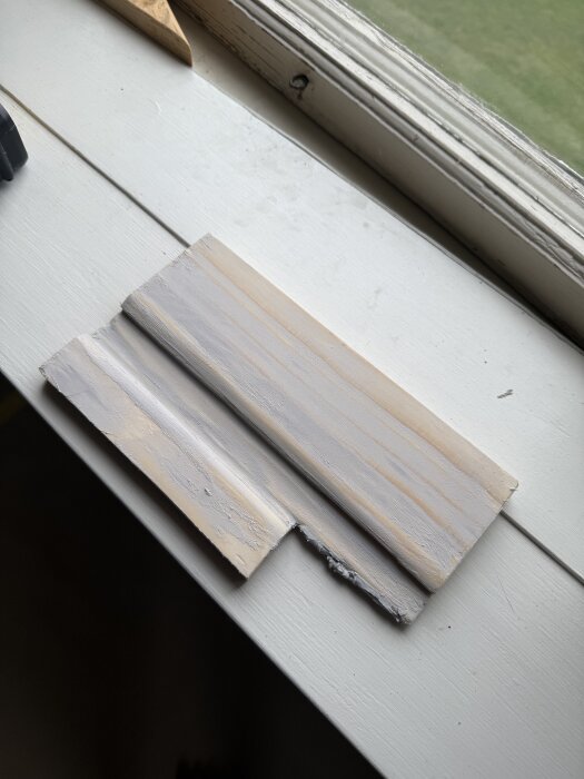 Närbild på en bit fräst byggplywood placerad på en ljus fönsterbräda.