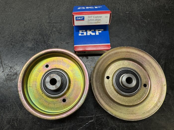 Två löphjul med fasta lager från SKF ligger på en svart yta bredvid två blå och röda SKF Explorer-kartonger.